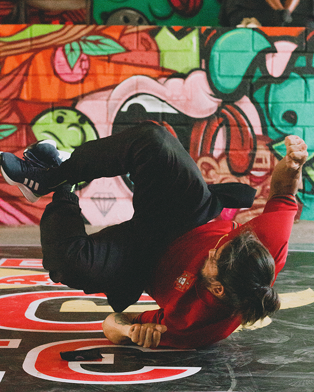 Young man break-dancing in front of graffiti wall