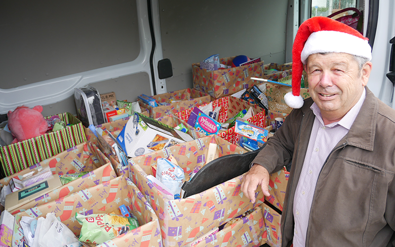 Mayor Volke in front of an open van filled with Christmas gifts
