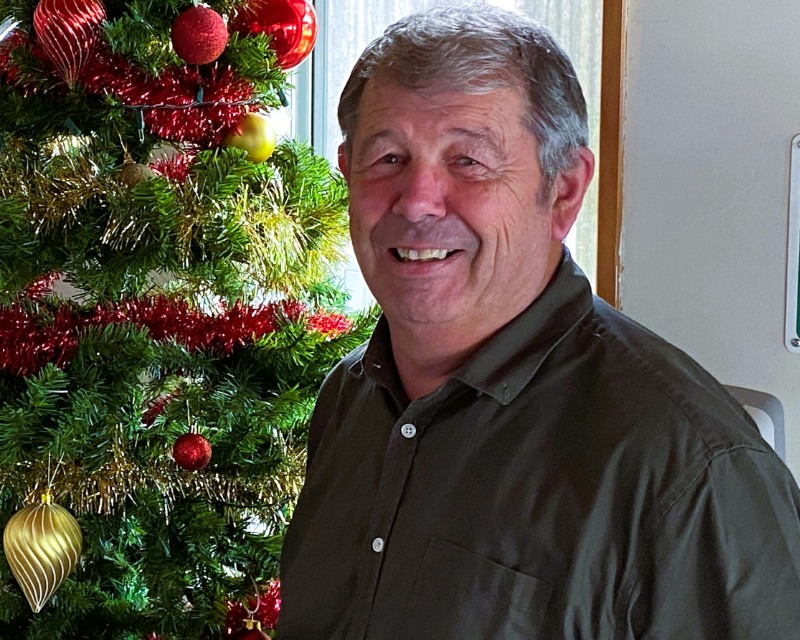 Mayor Neil Volzke, smiling and standing next to the Christmas tree in our Service Centre