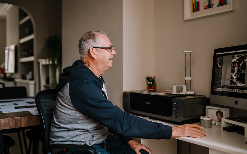 Retired man uses a computer in his home